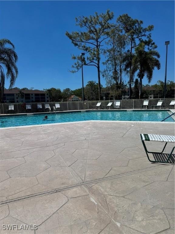 community pool with a patio and fence