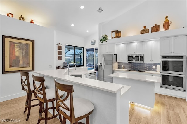 kitchen with tasteful backsplash, visible vents, a center island, stainless steel appliances, and a sink