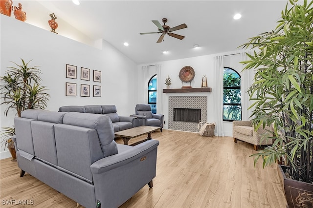 living room with a wealth of natural light, lofted ceiling, light wood-style floors, and a ceiling fan