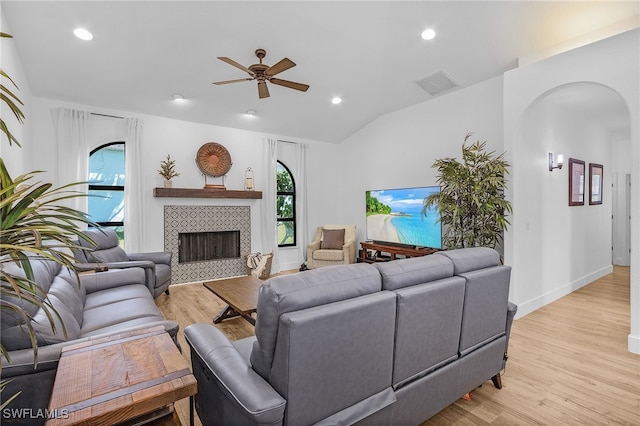 living room with visible vents, lofted ceiling, arched walkways, ceiling fan, and light wood-style floors