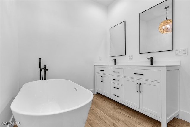 bathroom with double vanity, a soaking tub, a sink, and wood finished floors