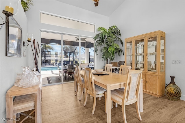 dining area featuring a ceiling fan, light wood-type flooring, and high vaulted ceiling