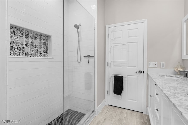 full bathroom with a tile shower, vanity, and wood tiled floor