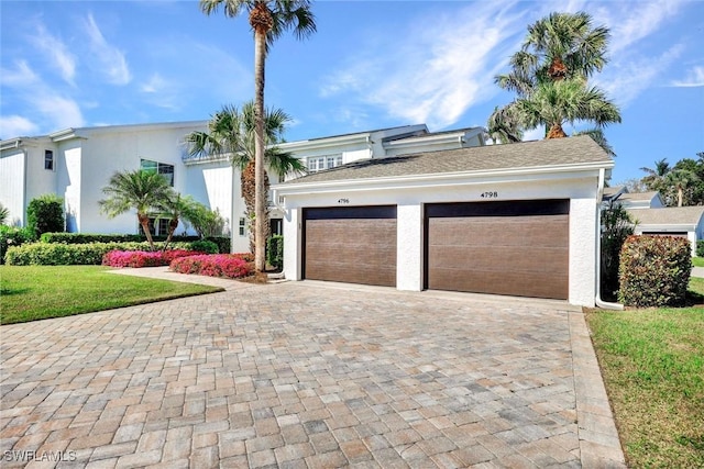 view of front of property with a front yard, decorative driveway, and stucco siding