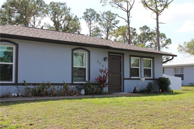 ranch-style home featuring stucco siding, a shingled roof, and a front yard