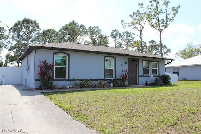 ranch-style home featuring stucco siding, driveway, and a front lawn