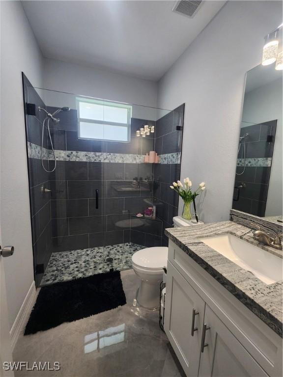 bathroom featuring visible vents, toilet, a stall shower, and vanity