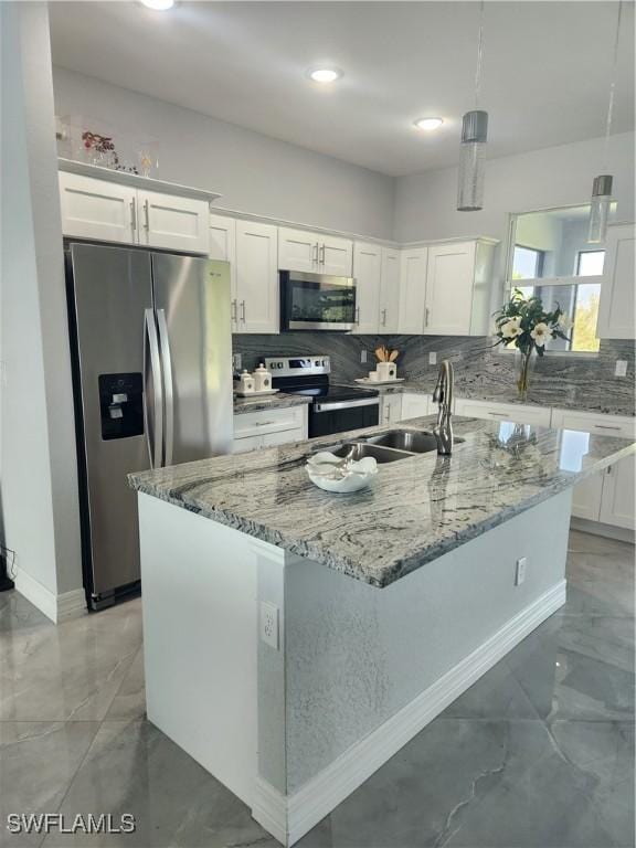 kitchen featuring an island with sink, light stone counters, backsplash, stainless steel appliances, and white cabinets