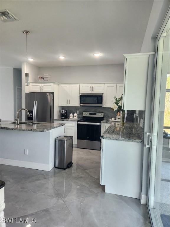 kitchen featuring visible vents, appliances with stainless steel finishes, dark stone counters, and a sink