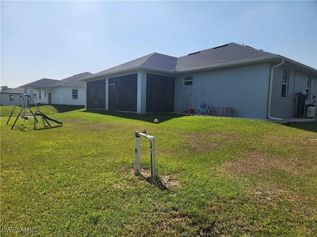 rear view of house featuring stucco siding, a lawn, and a sunroom