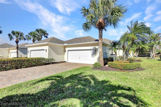 view of front of property with an attached garage, a front lawn, decorative driveway, and stucco siding