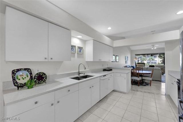 kitchen featuring a peninsula, a sink, white cabinetry, light countertops, and dishwasher