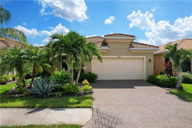 mediterranean / spanish-style house with stucco siding, decorative driveway, a garage, and a tile roof