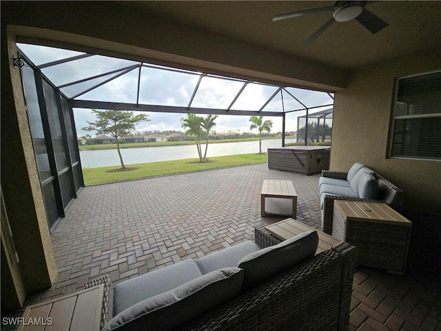 view of patio / terrace with glass enclosure, an outdoor living space, a hot tub, ceiling fan, and a water view