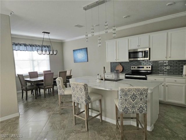 kitchen featuring a kitchen bar, ornamental molding, backsplash, white cabinetry, and appliances with stainless steel finishes