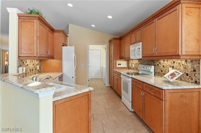 kitchen featuring white appliances, light stone countertops, washer / dryer, a peninsula, and vaulted ceiling