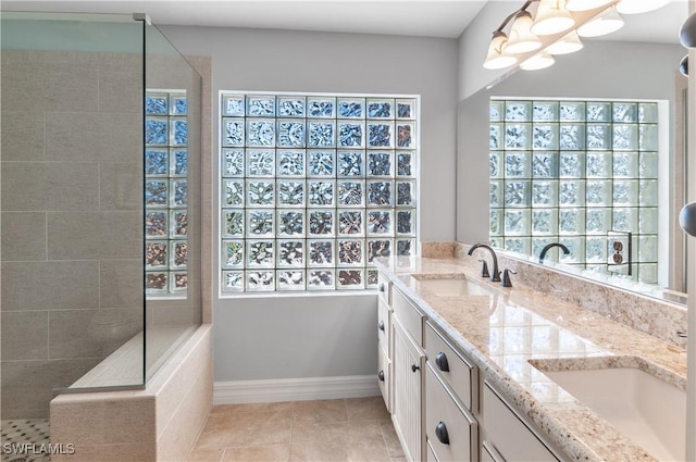 bathroom featuring baseboards, double vanity, a sink, a walk in shower, and a notable chandelier