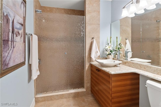 bathroom featuring tile patterned floors, toilet, a stall shower, and vanity