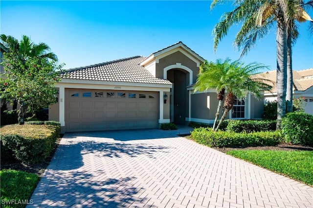 view of front of home featuring decorative driveway, a tile roof, an attached garage, and stucco siding