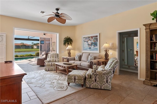 living area with visible vents, a water view, and ceiling fan