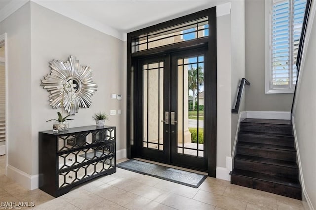 entrance foyer with stairs, baseboards, and french doors