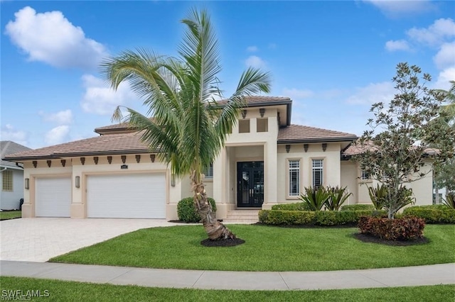 view of front of house with an attached garage, a tiled roof, decorative driveway, stucco siding, and a front lawn