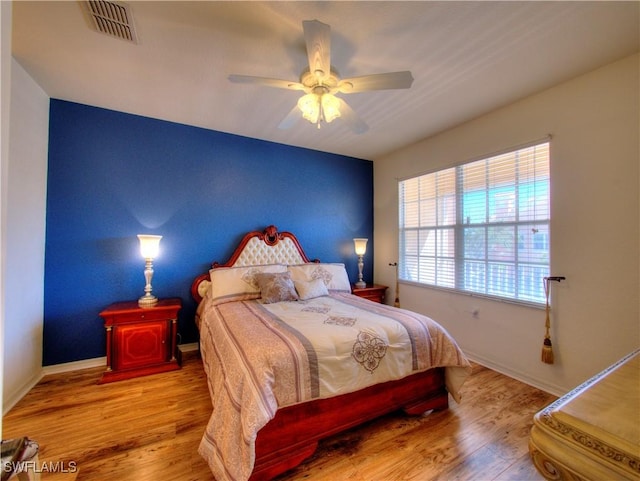 bedroom featuring ceiling fan, wood finished floors, visible vents, and baseboards