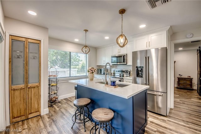 618 SE 26th St, Cape Coral, FL 33904 - kitchen with appliances with stainless steel finishes, light wood finished floors, light countertops, an island with sink, and white cabinetry