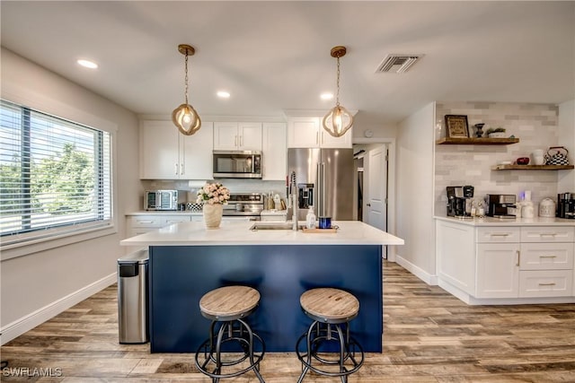 618 SE 26th St, Cape Coral, FL 33904 - kitchen with stainless steel appliances, white cabinetry, light countertops, tasteful backsplash, and a kitchen bar