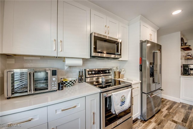 618 SE 26th St, Cape Coral, FL 33904 - kitchen with stainless steel appliances, wood finished floors, white cabinets, tasteful backsplash, and light countertops