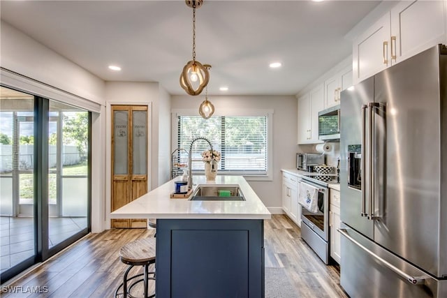 618 SE 26th St, Cape Coral, FL 33904 - kitchen with stainless steel appliances, a sink, white cabinets, light countertops, and a kitchen island with sink