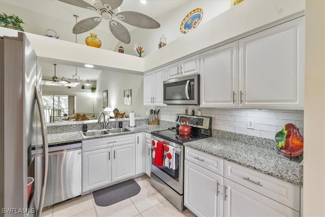 kitchen featuring decorative backsplash, white cabinets, stainless steel appliances, and a sink