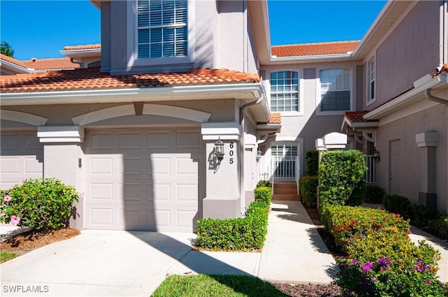 view of front of property with a tiled roof, a garage, driveway, and stucco siding