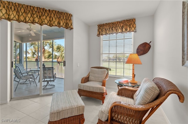 living area with light tile patterned floors, ceiling fan, and baseboards