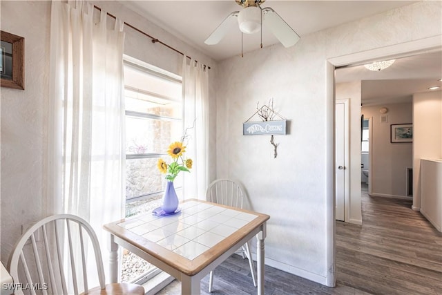 dining room with baseboards, a healthy amount of sunlight, dark wood-style floors, and a ceiling fan