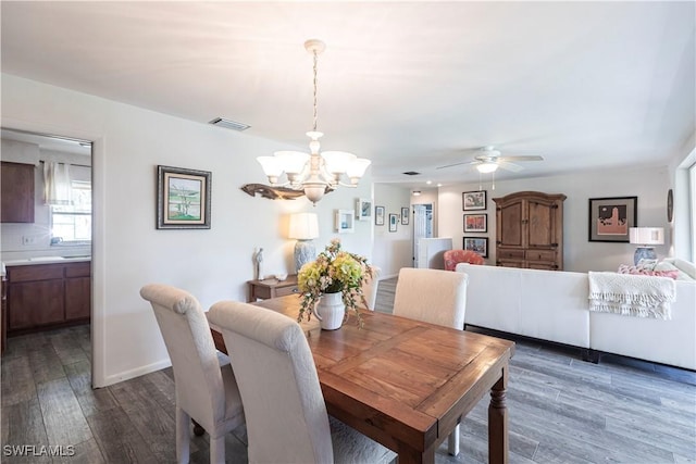 dining space featuring ceiling fan with notable chandelier, wood finished floors, visible vents, and baseboards