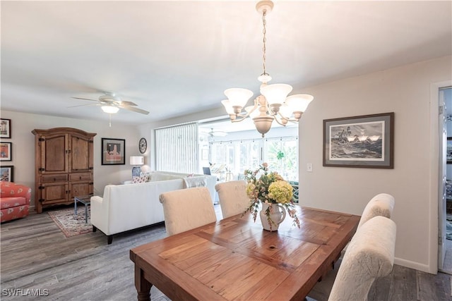 dining room featuring baseboards, wood finished floors, and ceiling fan with notable chandelier