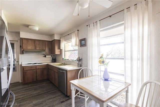 kitchen with dark wood-type flooring, under cabinet range hood, stainless steel appliances, a ceiling fan, and a sink