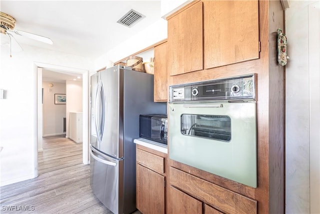 kitchen featuring visible vents, freestanding refrigerator, ceiling fan, oven, and black microwave