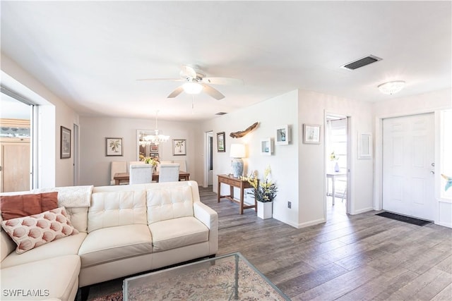 living room featuring ceiling fan with notable chandelier, wood finished floors, visible vents, and baseboards