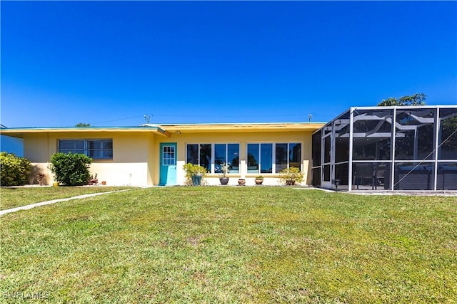 back of house with glass enclosure, a lawn, and stucco siding