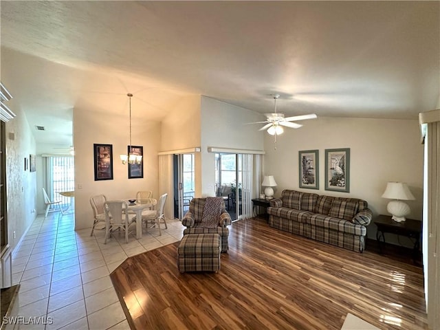 living area with plenty of natural light, high vaulted ceiling, wood finished floors, and ceiling fan with notable chandelier