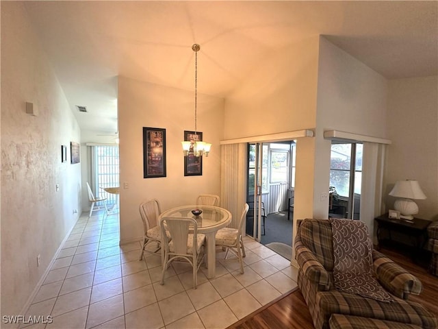 dining space with a notable chandelier, visible vents, a high ceiling, light tile patterned flooring, and baseboards