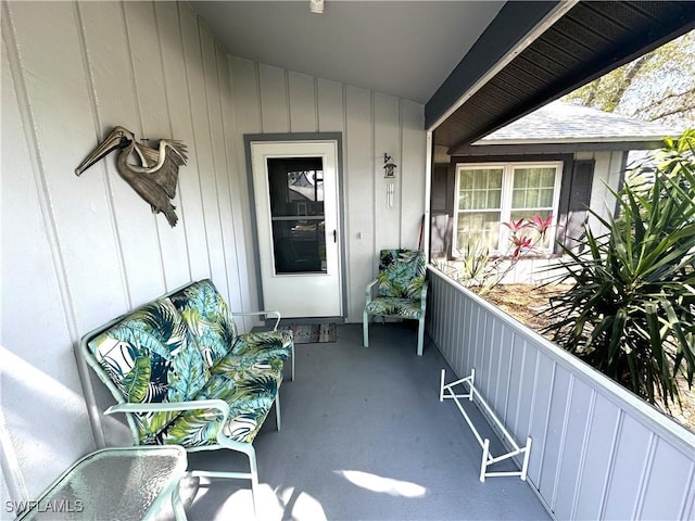 entrance to property featuring roof with shingles, a porch, and board and batten siding