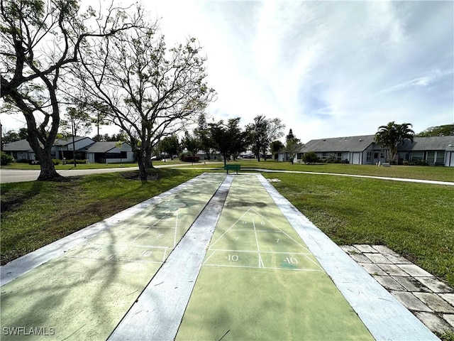 view of community featuring shuffleboard, a yard, and a residential view