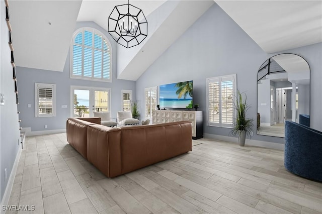 living area featuring light wood-type flooring, arched walkways, baseboards, and a chandelier