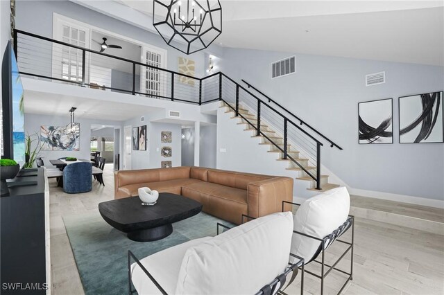 living room featuring visible vents, light wood-style floors, a towering ceiling, and stairway