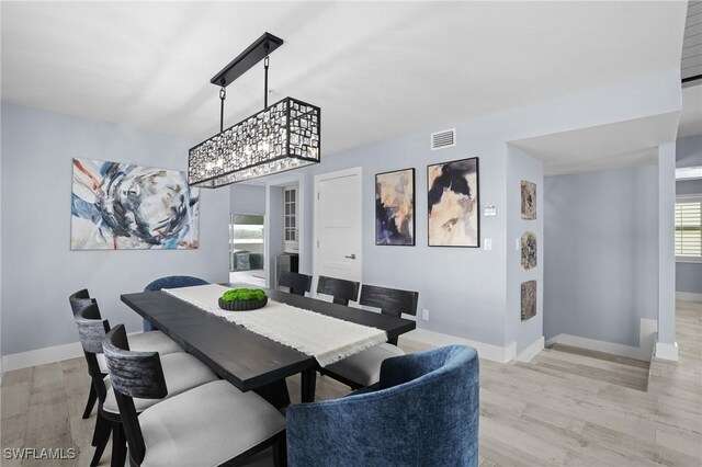 dining space featuring visible vents, light wood-style flooring, and baseboards