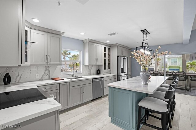 kitchen with a sink, stainless steel appliances, glass insert cabinets, and gray cabinets