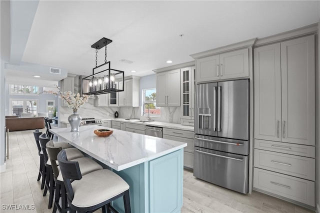 kitchen featuring visible vents, gray cabinets, stainless steel appliances, glass insert cabinets, and tasteful backsplash